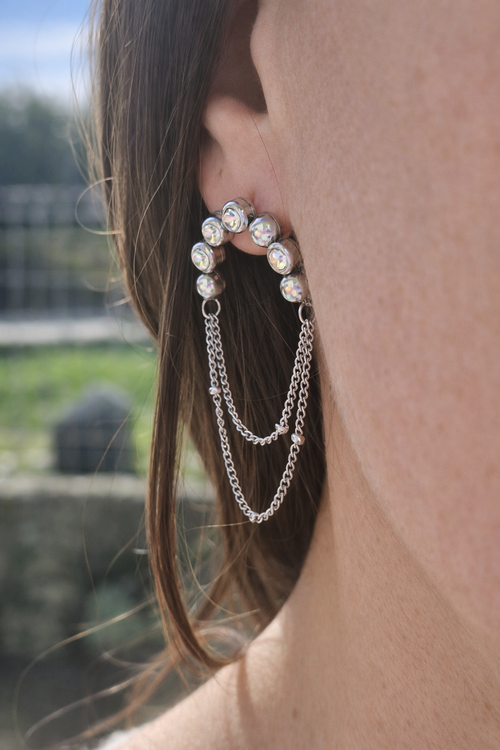 Boucles d’oreilles JOY en acier inoxydable, disponibles en doré et argenté. Design élégant avec chaînes et perles, parfait pour un look chic, tendance et lumineux été comme hiver.